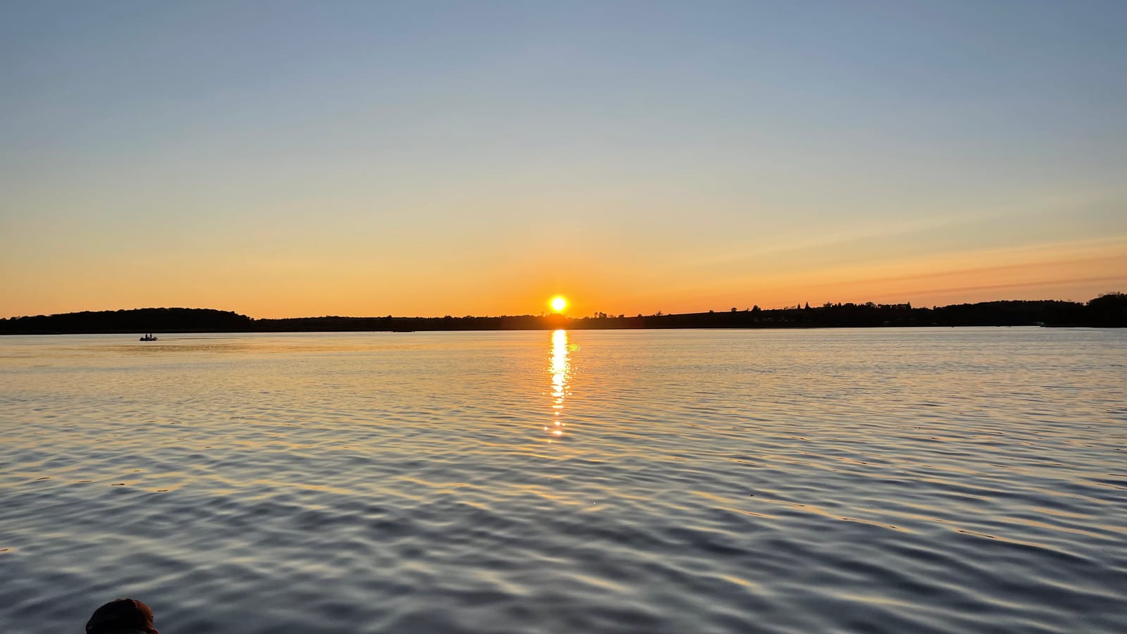 The sun melting into Rice Lake, its reflection a column of amber across the water